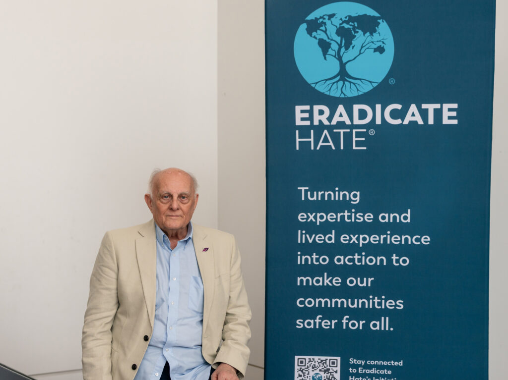 An Eradicate Hate speaker standing next to the welcome sign.